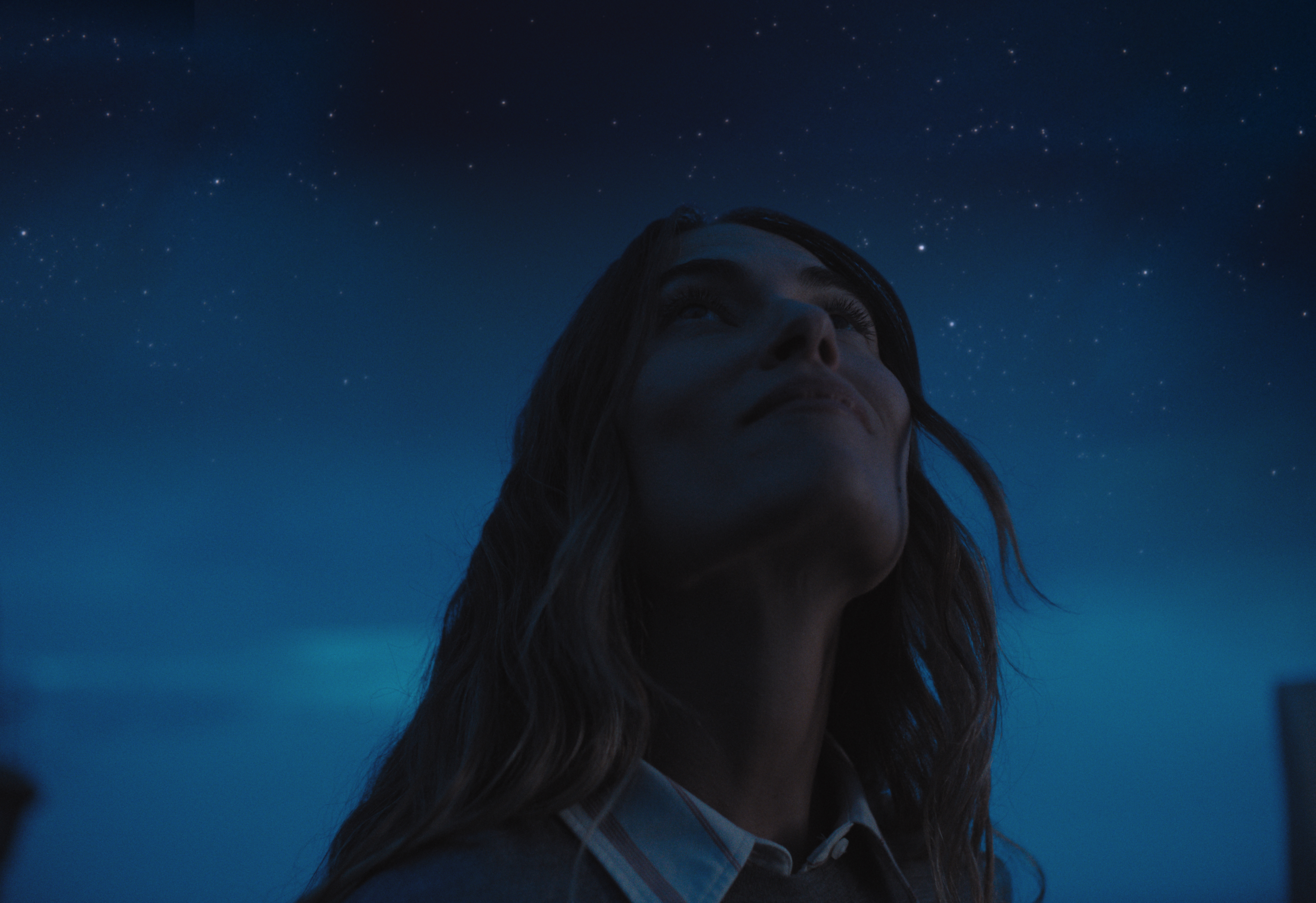 Woman looking up under a night sky.